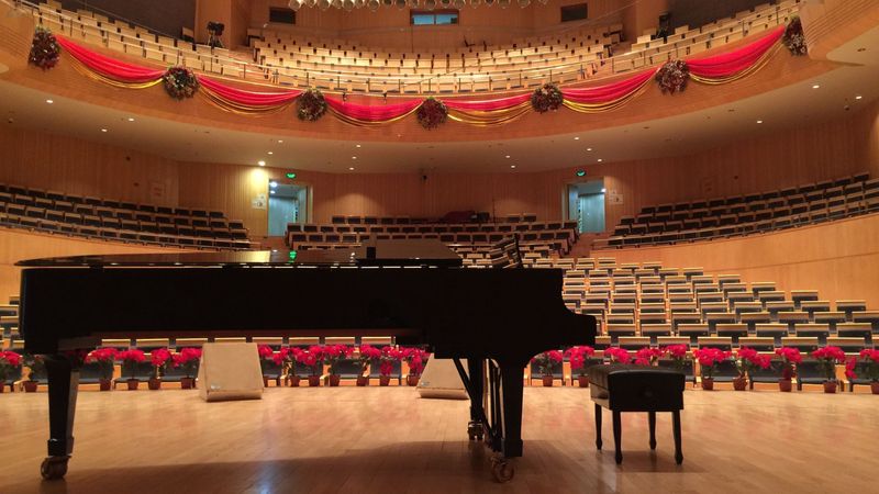 A grand piano sits in front of a stage